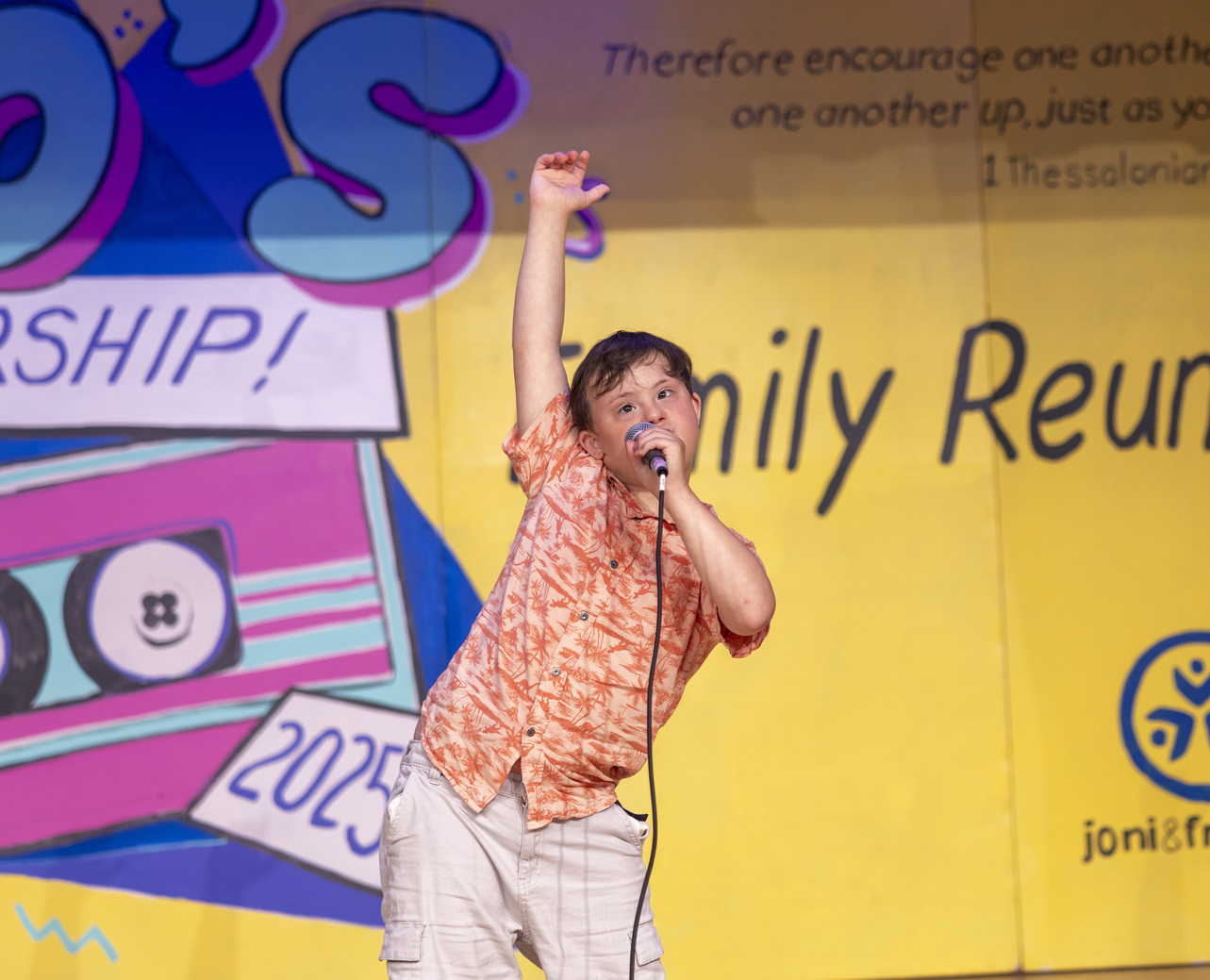 Teddy, a boy with Down syndrome, singing "Let It Go" into a microphone during a Family Retreat.