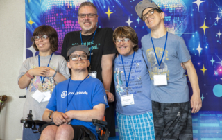 Rick and Roseanne smiling with their three children in front of a disco banner backdrop behind them, radiating joy and faith at Joni and Friends Family Retreat.