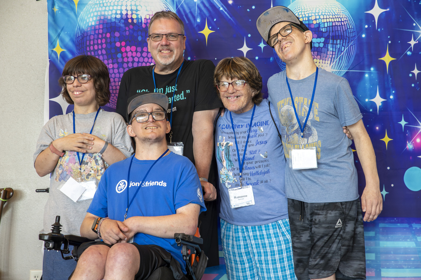 Rick and Roseanne smiling with their three children in front of a disco banner backdrop behind them, radiating joy and faith at Joni and Friends Family Retreat.