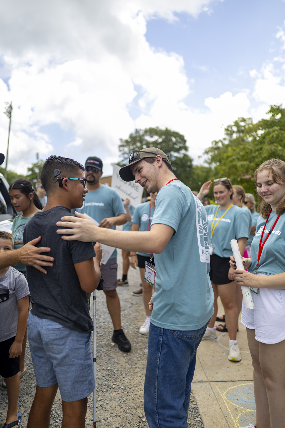 Landon being welcomed by his buddy Carter, with people in the background.