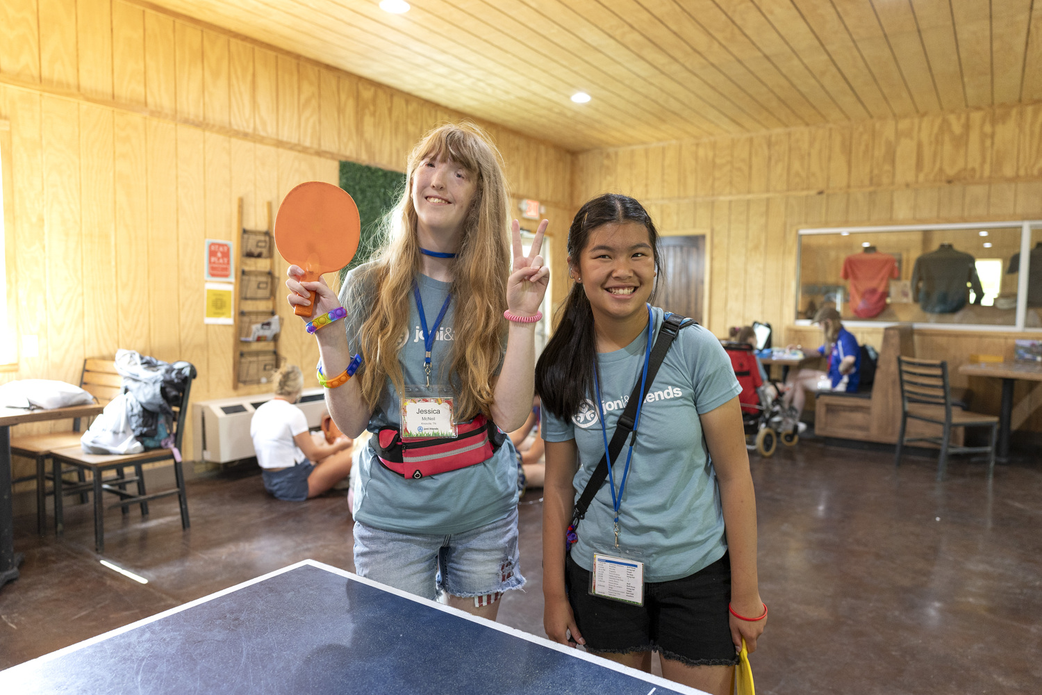 Brooklyn and Jessica smiling together in front of a ping pong table.