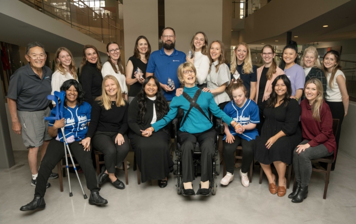 Joni and Friends team displaying their four Prism Awards, with Joni Eareckson Tada at the center, surrounded by smiling staff enjoying the moment.