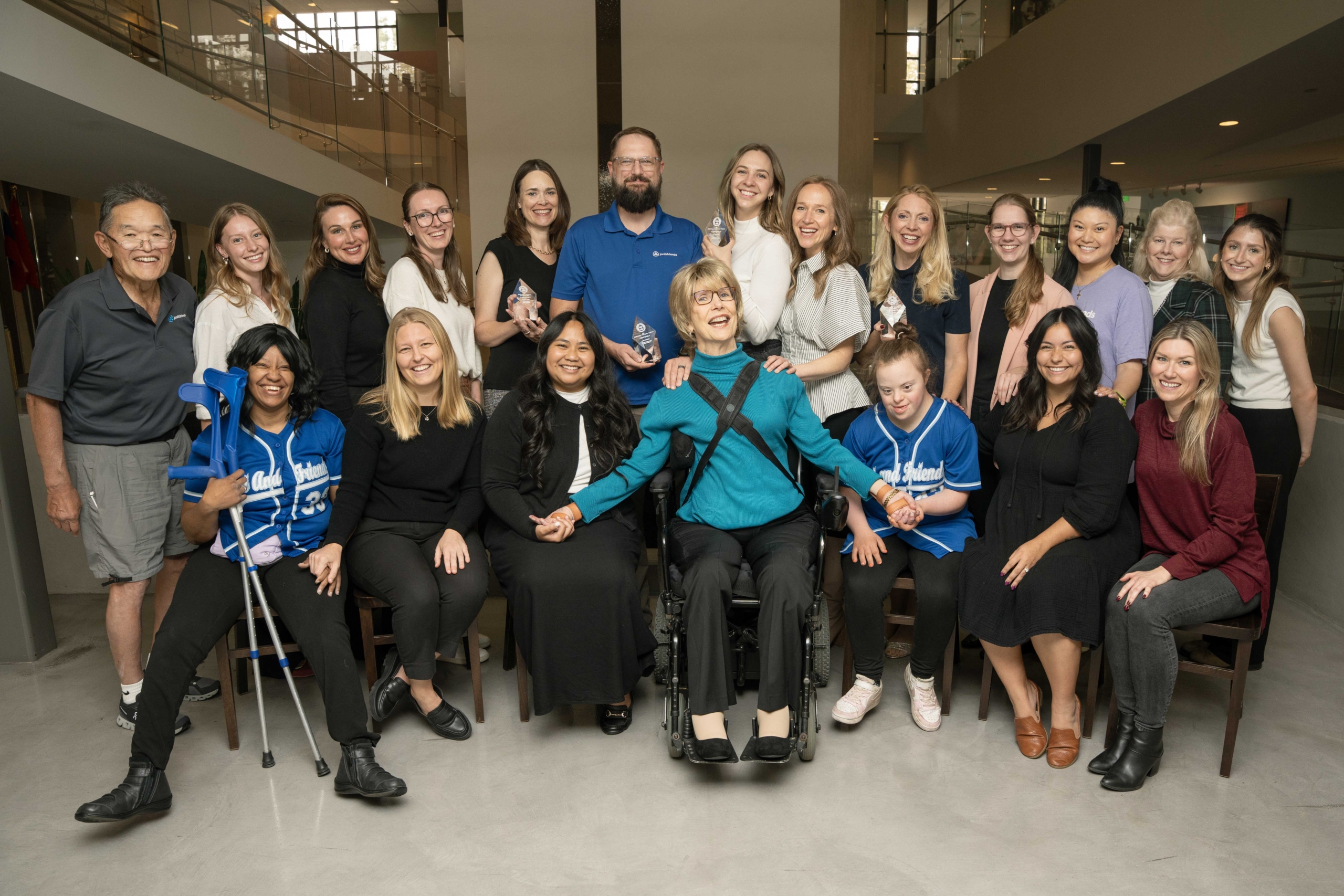 Joni and Friends team displaying their four Prism Awards, with Joni Eareckson Tada at the center, surrounded by smiling staff enjoying the moment.