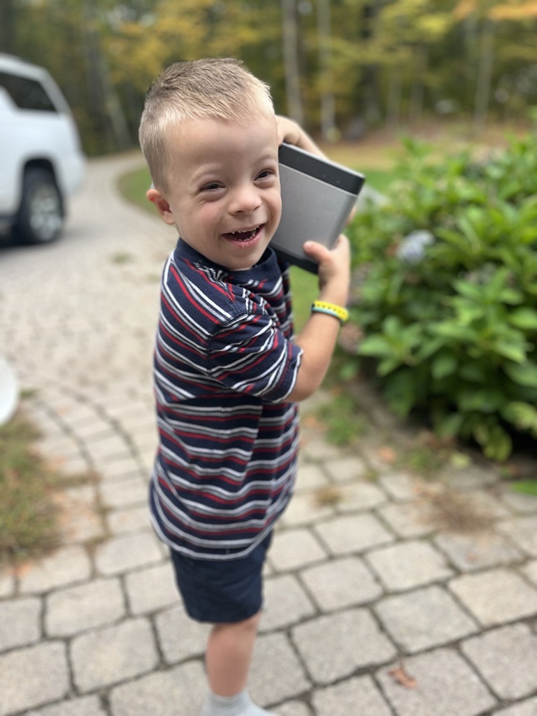 Jacob, a young boy with Down Syndrome, smiling brightly.