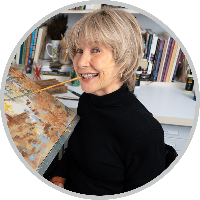 Joni Eareckson Tada smiling at the camera while painting with a brush held in her mouth.