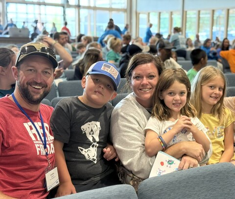 Austin, Melissa, and their three children sitting together and smiling at the camera.