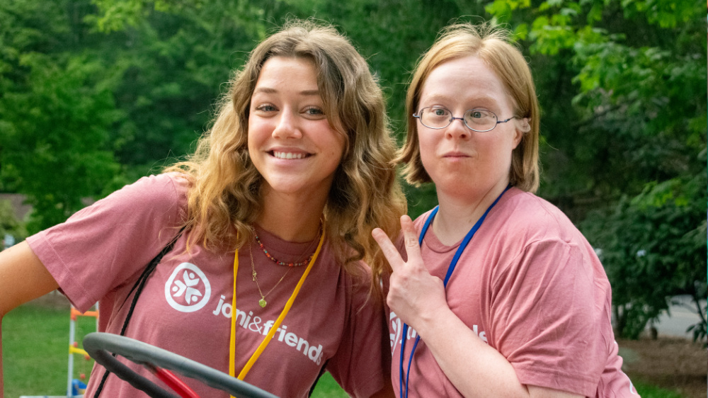 A volunteer and camper pose for a photo at Family Retreat