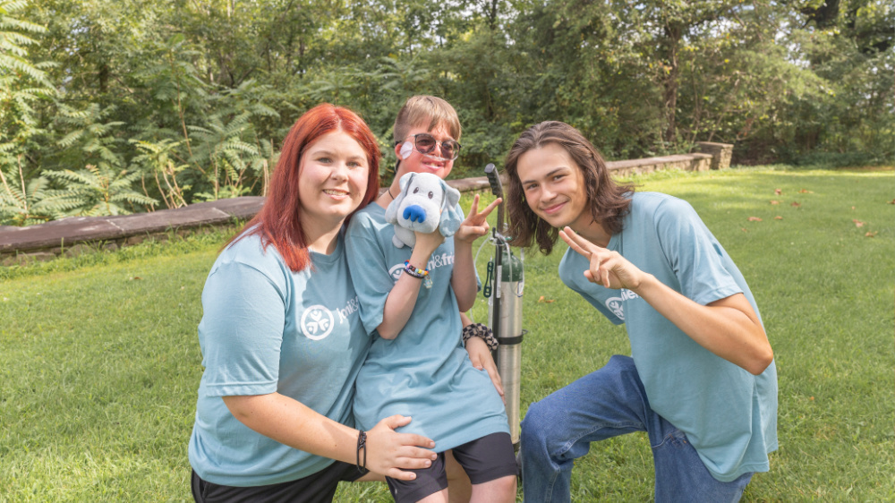 A camper and volunteers pose for a photo at Family Retreat
