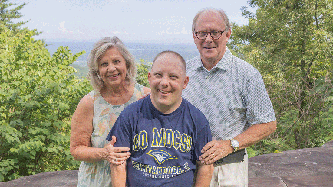 Mother, father, and son stand together smiling at the camera