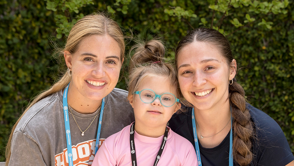 A camper and volunteers pose for a photo at Family Retreat