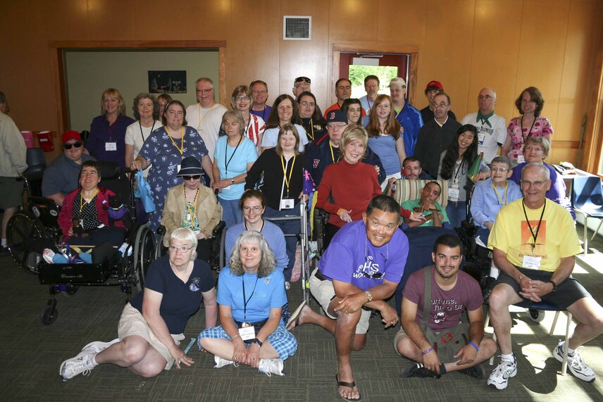 Joni Eareckson Tada, Ken Tada, and Bruce in his wheelchair in a group photo with many people, including some using wheelchairs and walkers.