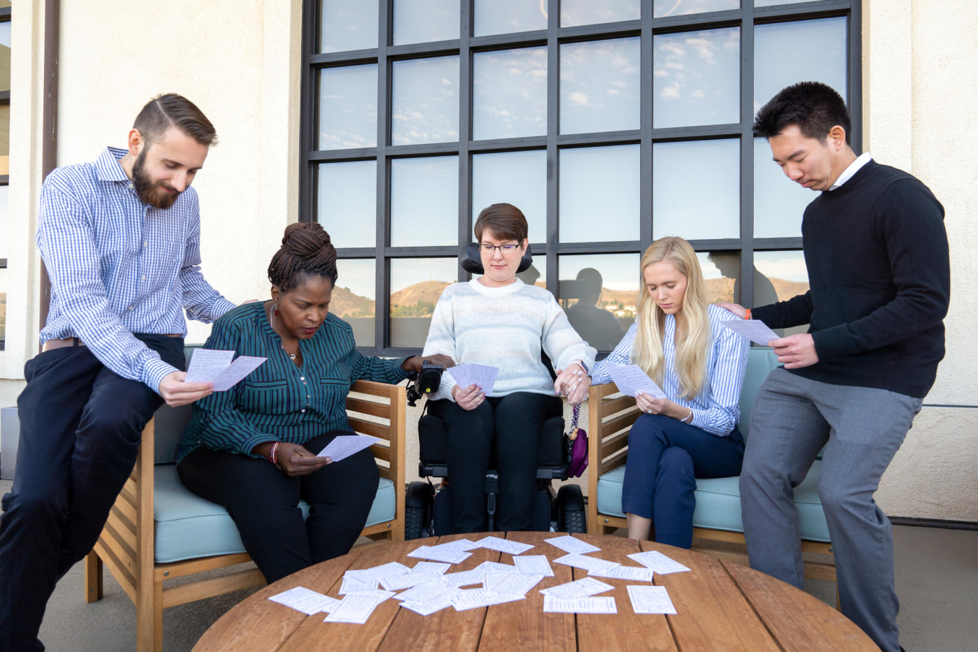 Five people gathered in prayer, looking at written prayer requests.