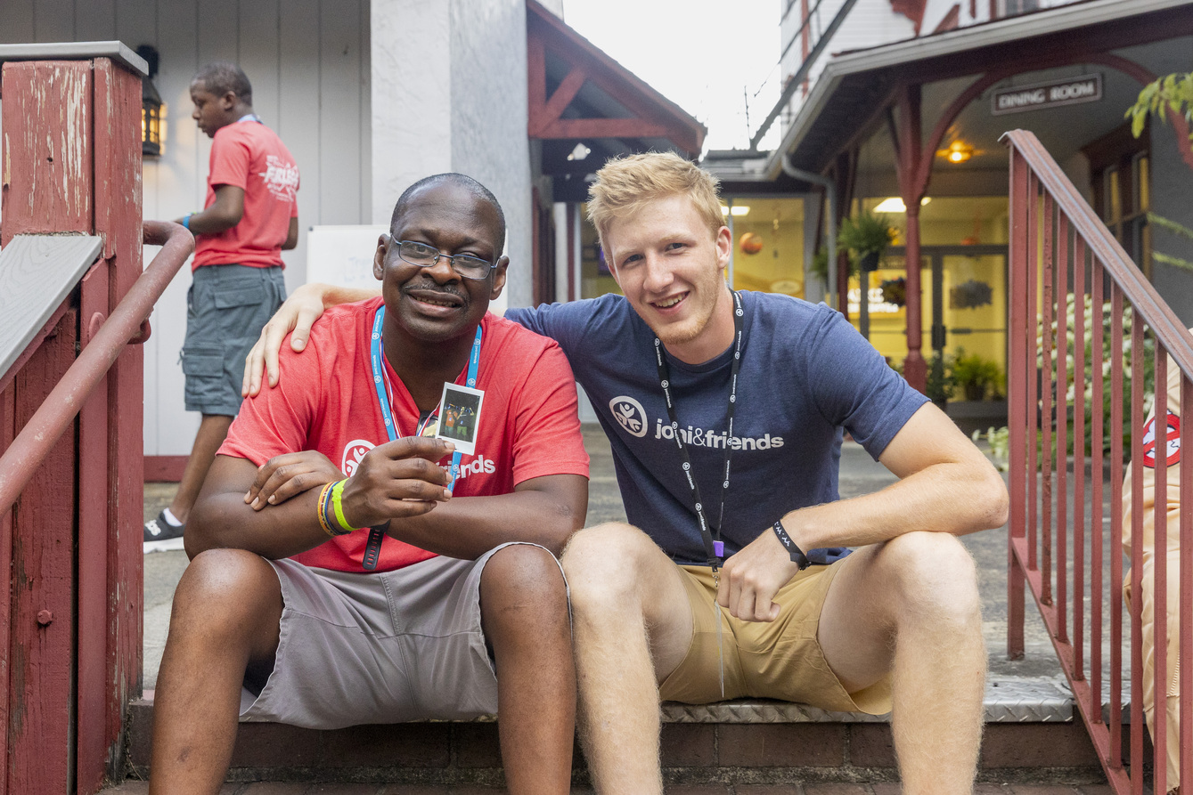 Deondre and his friend sitting on a stair step, smiling at the camera.