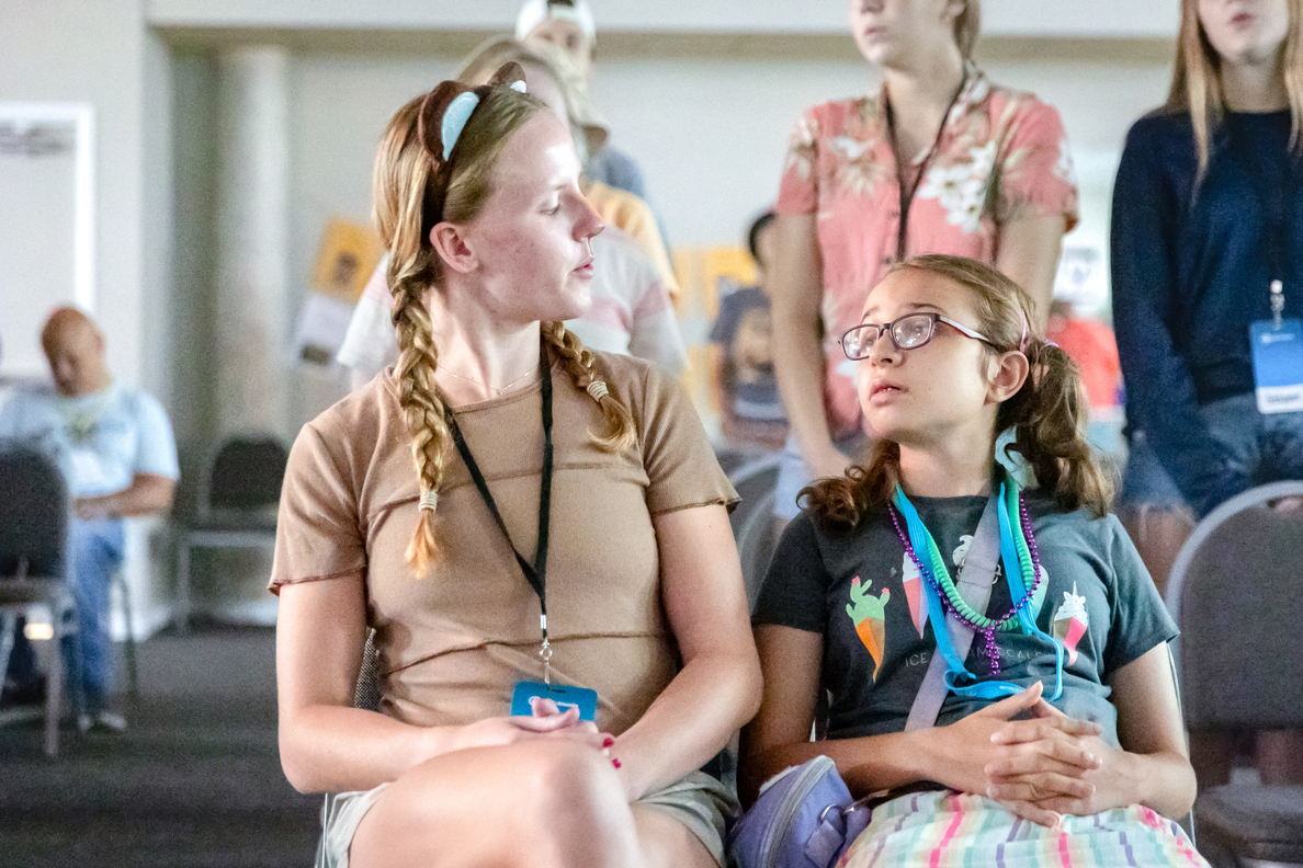 Lindsey and her buddy look at each other while sitting during worship.