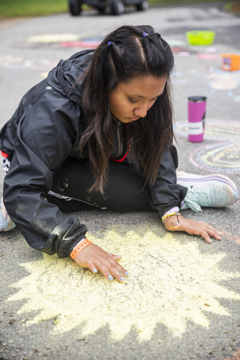 Sana sits on the ground, enjoying doing art.