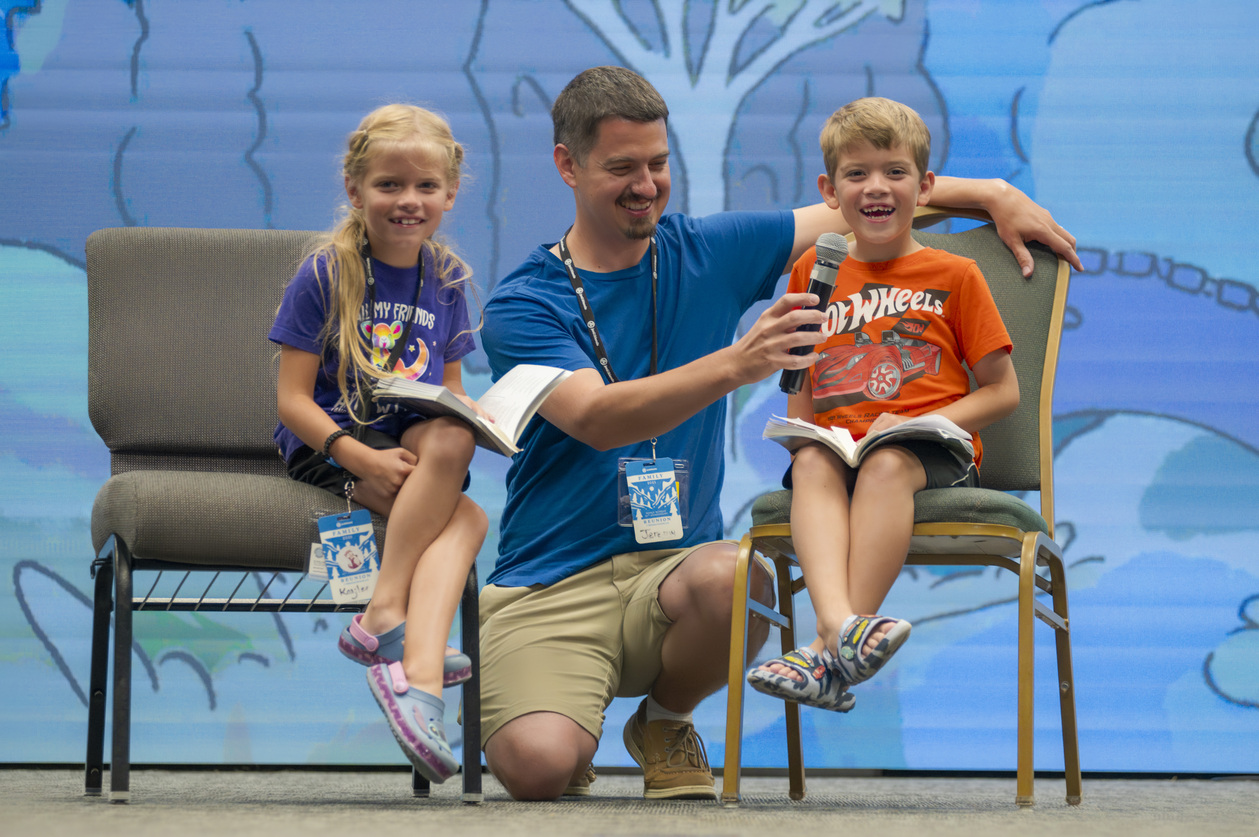 Kaylee, Jeremy, and William on stage during a talent show at the Family Retreat.