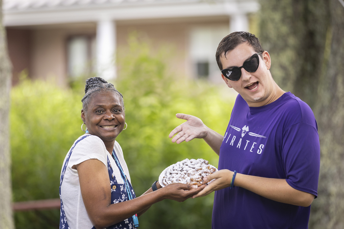 Fredrea shows off a funnel cake while standing next to a man at a Family Retreat.