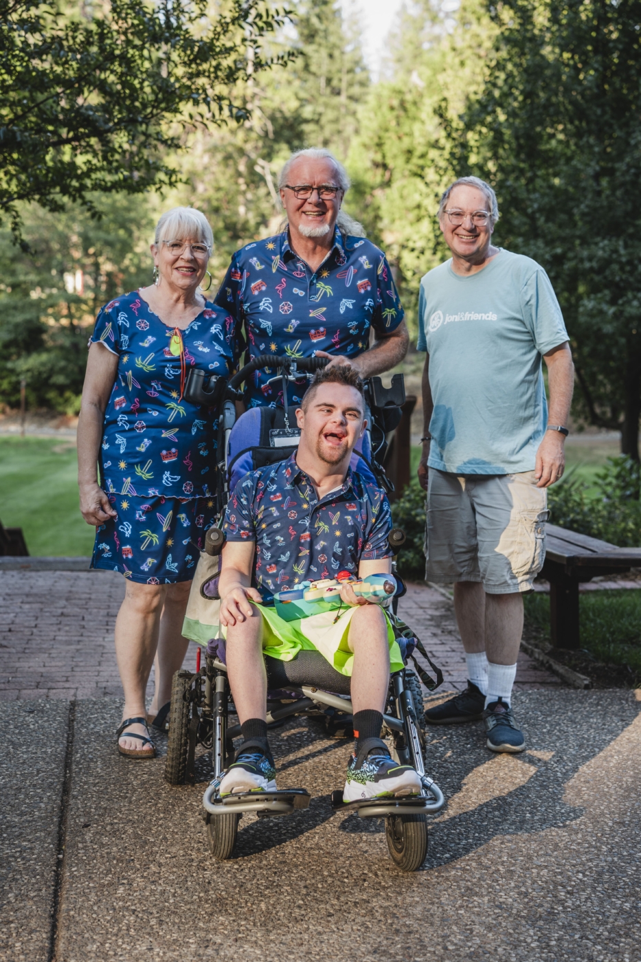 Darrell and Donnell smile with their son DJ, who has Down syndrome and uses a wheelchair, along with his buddy, Walter, at the Family Retreat.