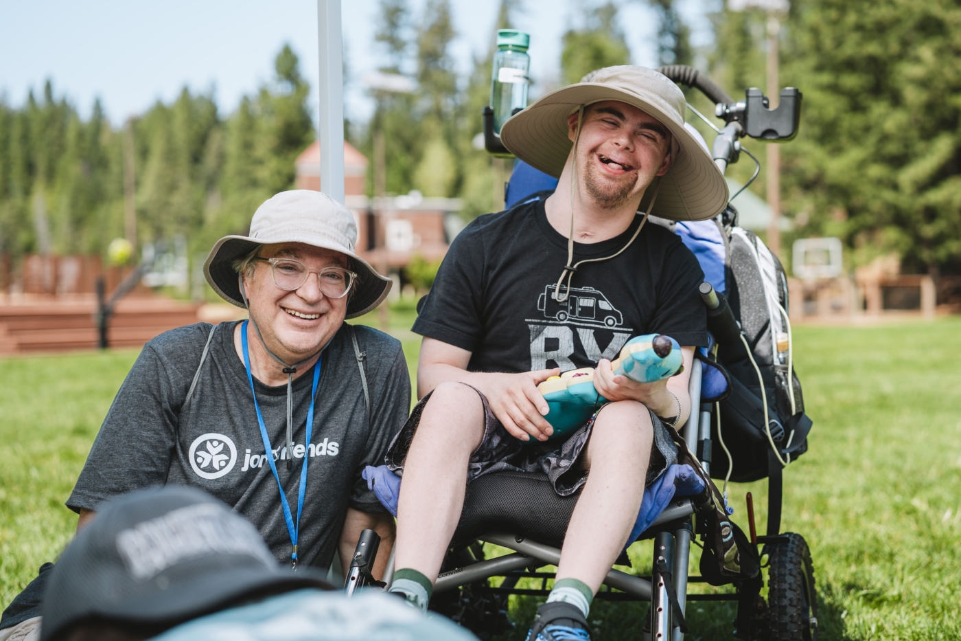 DJ smiles while sitting in his wheelchair with his buddy, Walter, during the Family Retreat.