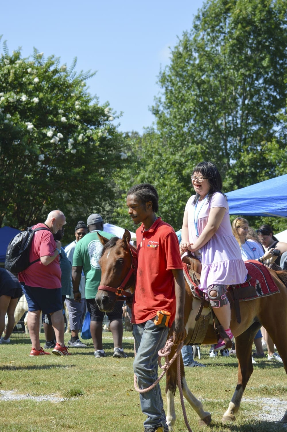Yan enjoying her time riding a horse, accompanied by a guide walking beside the horse.