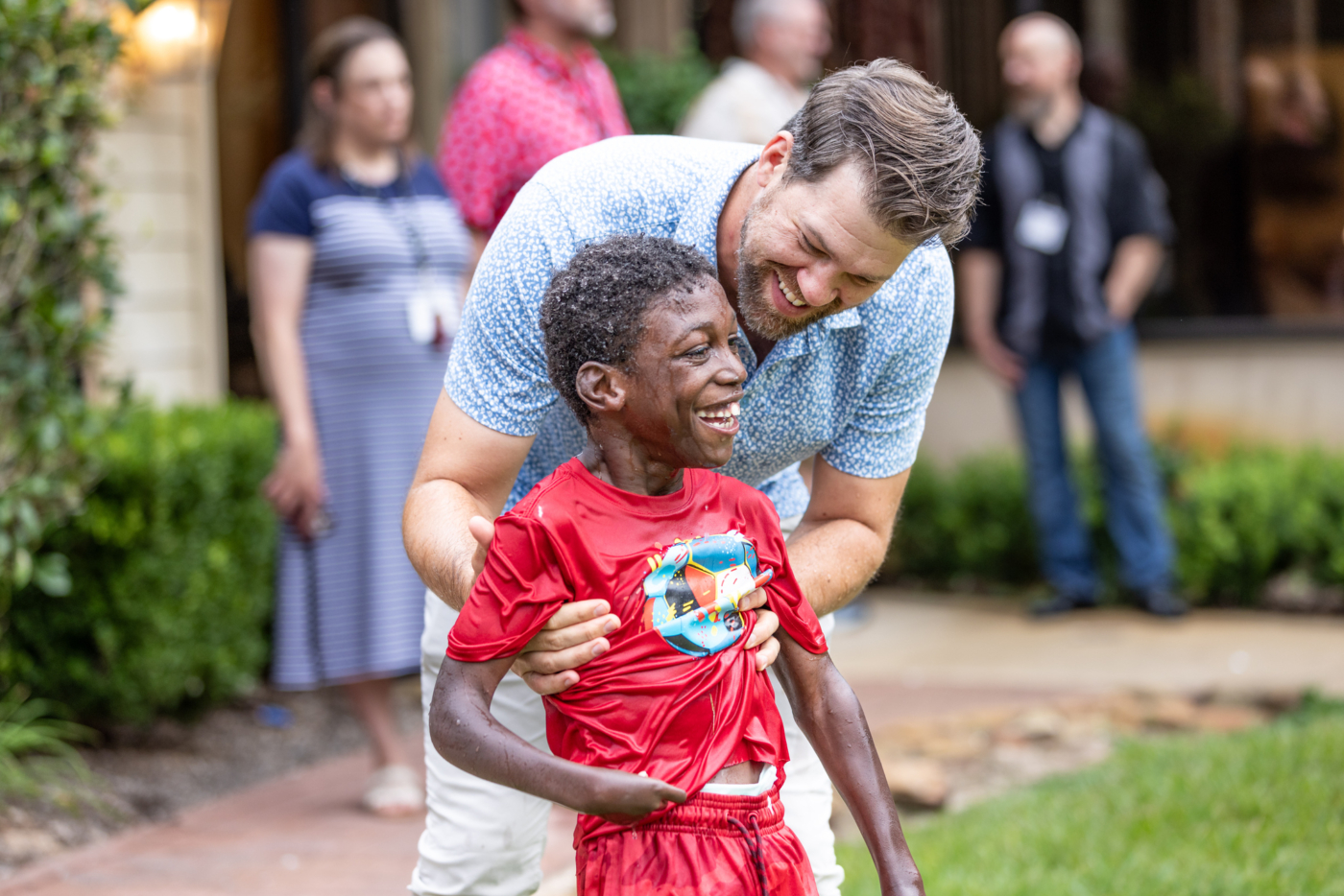 A boy enjoys the water with a man beside him, and both are smiling.