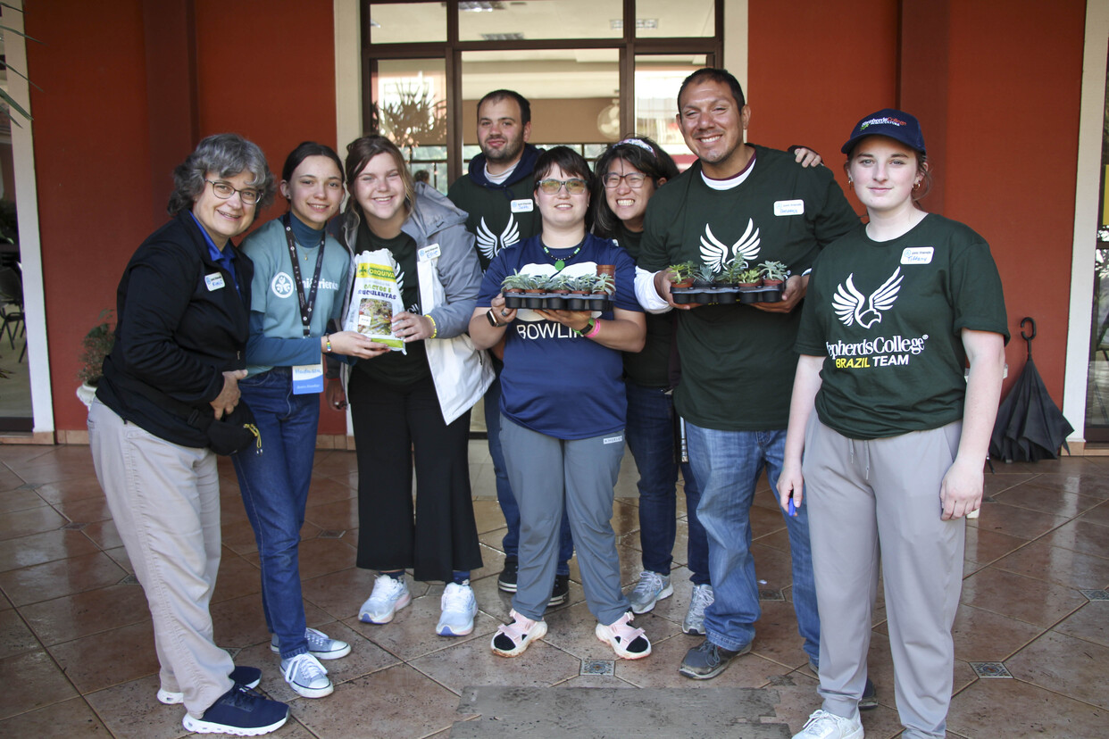 A group photo of Shepherds College interns with staff at Joni and Friends, some holding small potted plants.