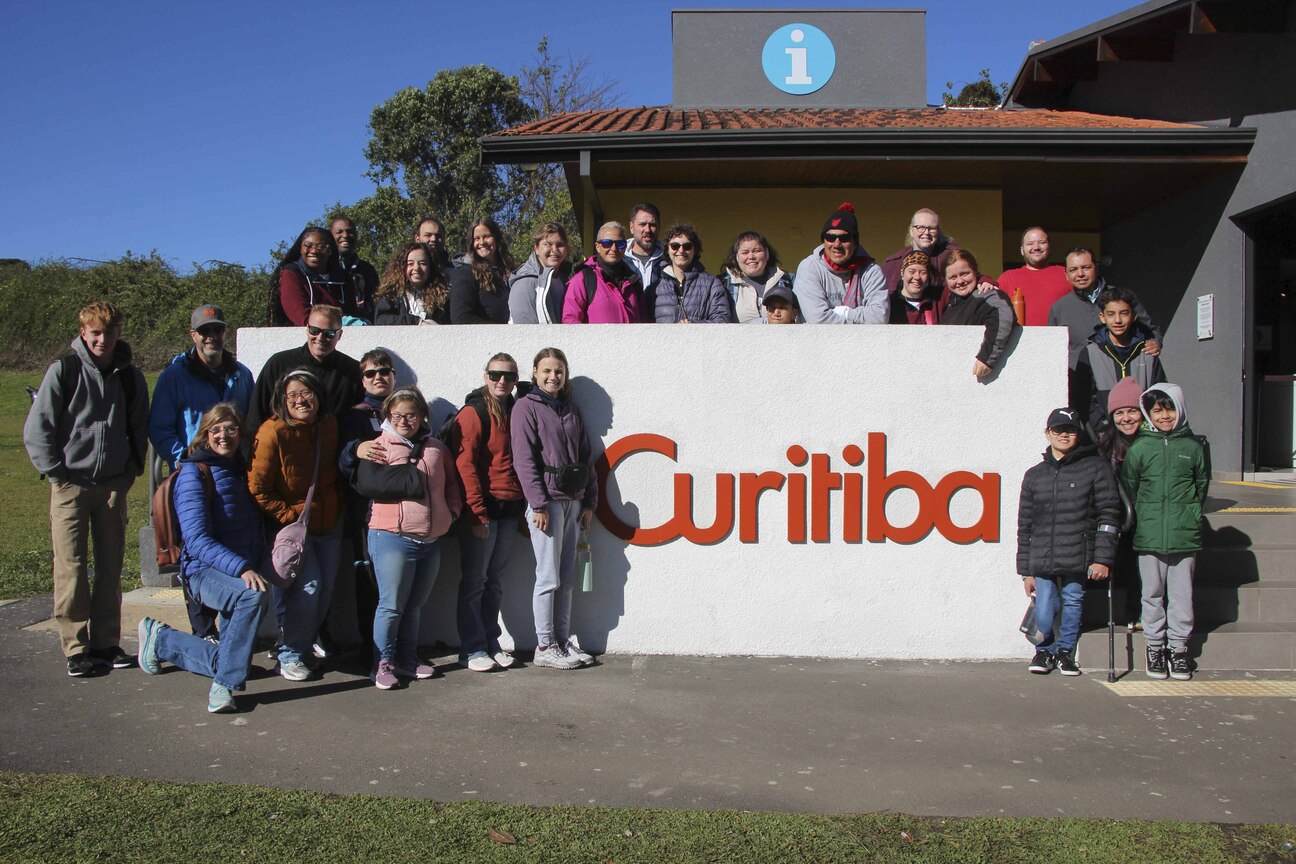 A group of Shepherds College interns in Brazil posing in front of an embedded wall with the word “Curitiba.”