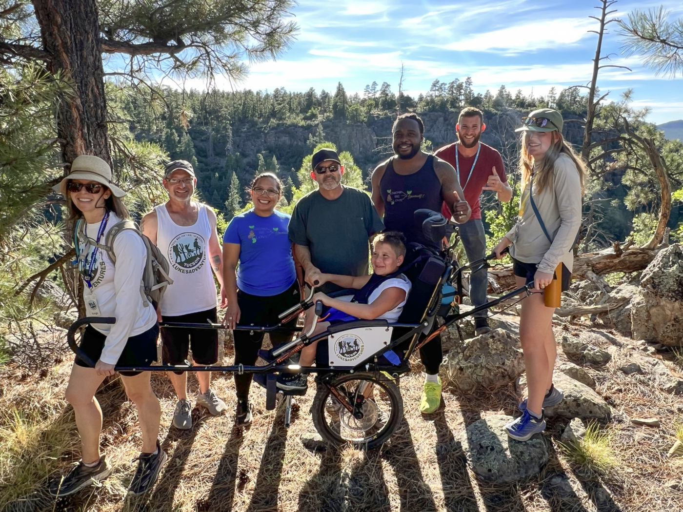 Conrad hikes with Luke 5 Adventures volunteers and his Warrior Getaway hero, Tholin Johnson, and they capture a photo together along the trail.