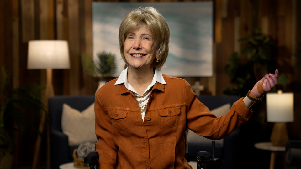 Joni Eareckson Tada smiling for the camera in a cozy living room setup.