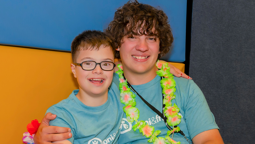 A camper and volunteer pose for a photo at Family Retreat