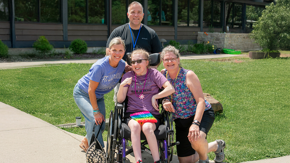 A family and volunteer pose for a photo at Family Retreat
