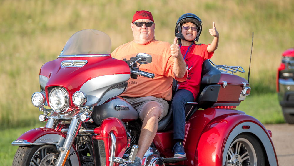 A volunteer and camper on a motorcycle.