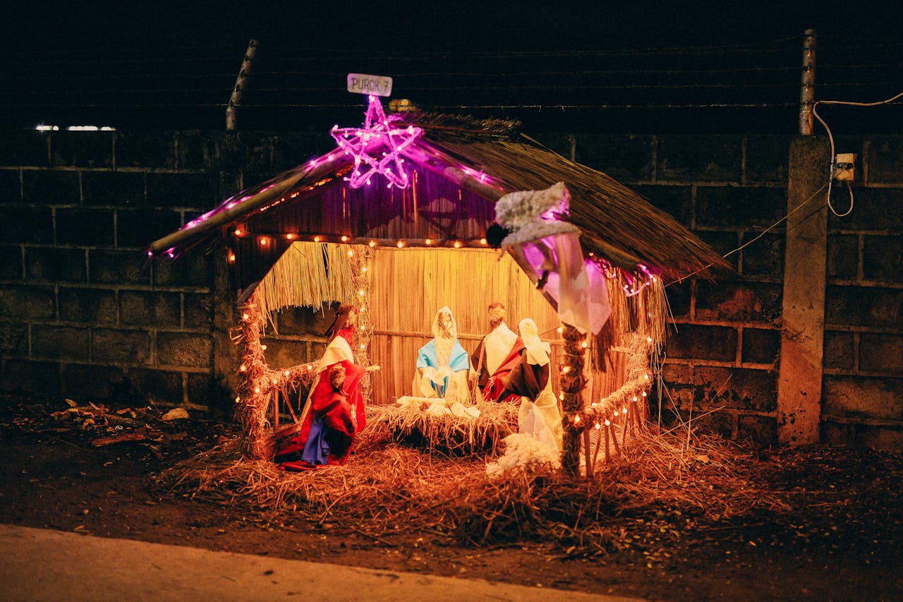A straw-and-wood nativity scene with Mary, Joseph, the baby in a manger, three kings, sheep, an angel flying above, and a star on top.