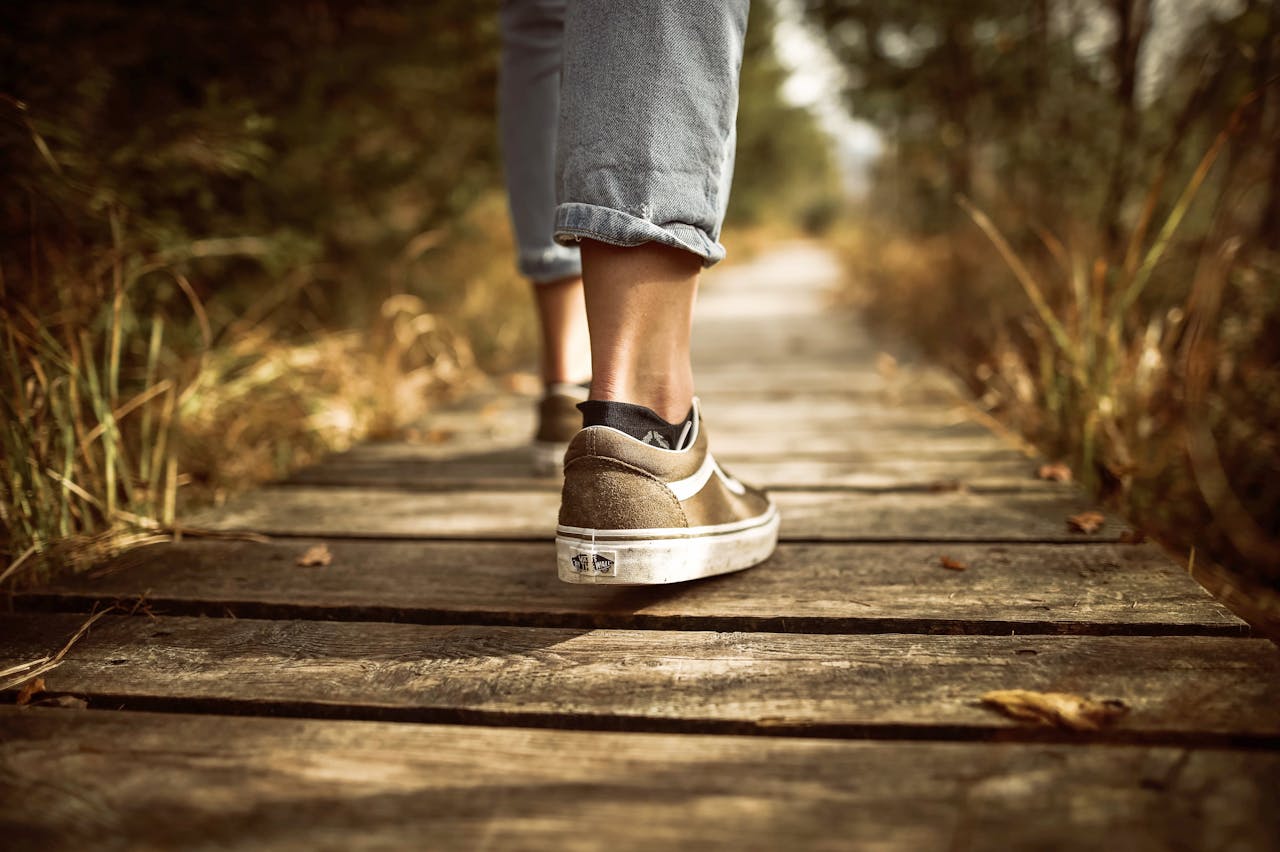 Close-up of a person’s shoes as they walk on a wooden pathway