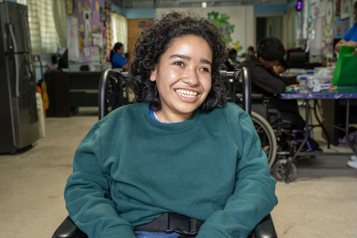 Memita smiles widely while other classmates appear in the background.