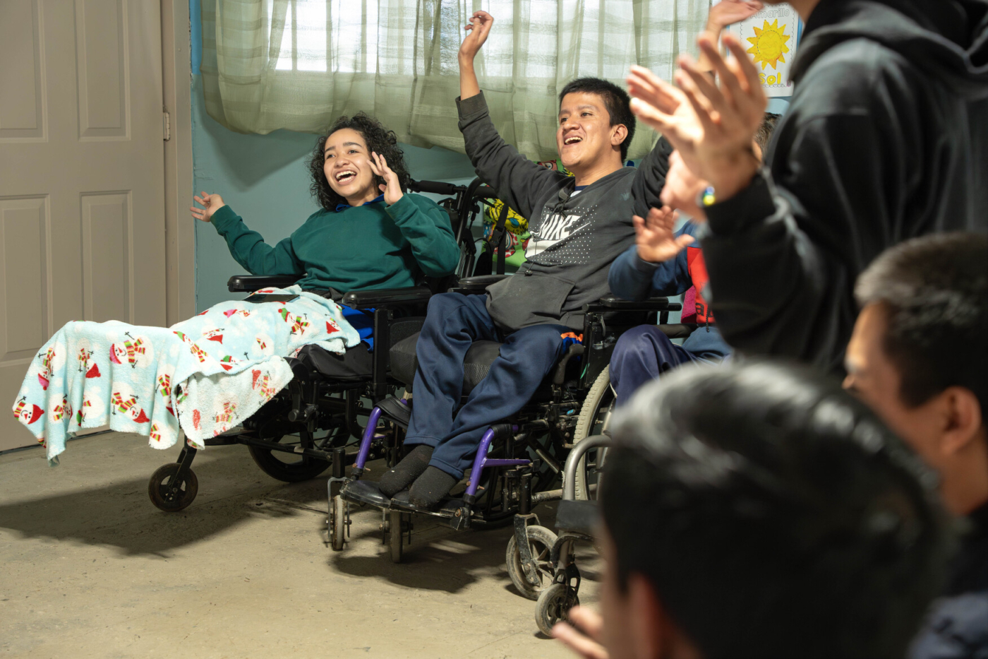 Javier smiling and worshiping next to another woman in her wheelchair.