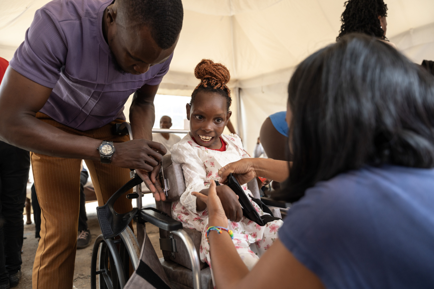 Praise sits in her wheelchair while Joni and Friends staff check her vitals.
