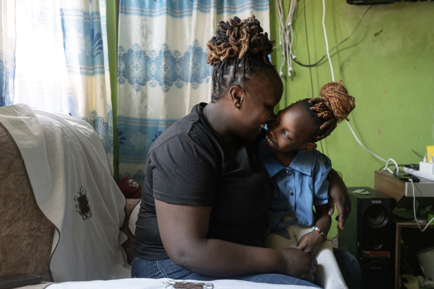 Praise sits on her mother Elizabeth’s lap as they smile at each other.
