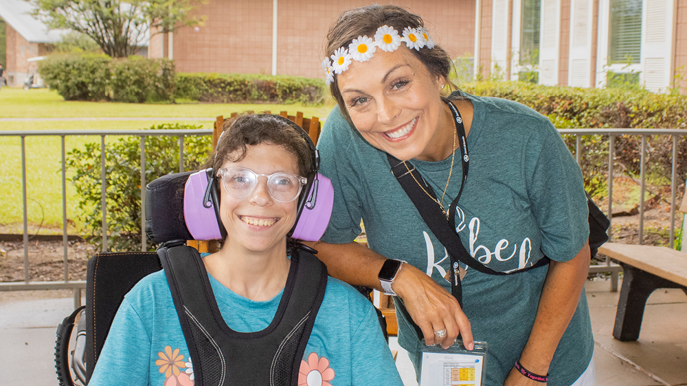A camper and volunteer pose for a photo at Family Retreat