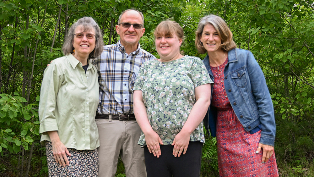 People pose for a photo in front of a forest background