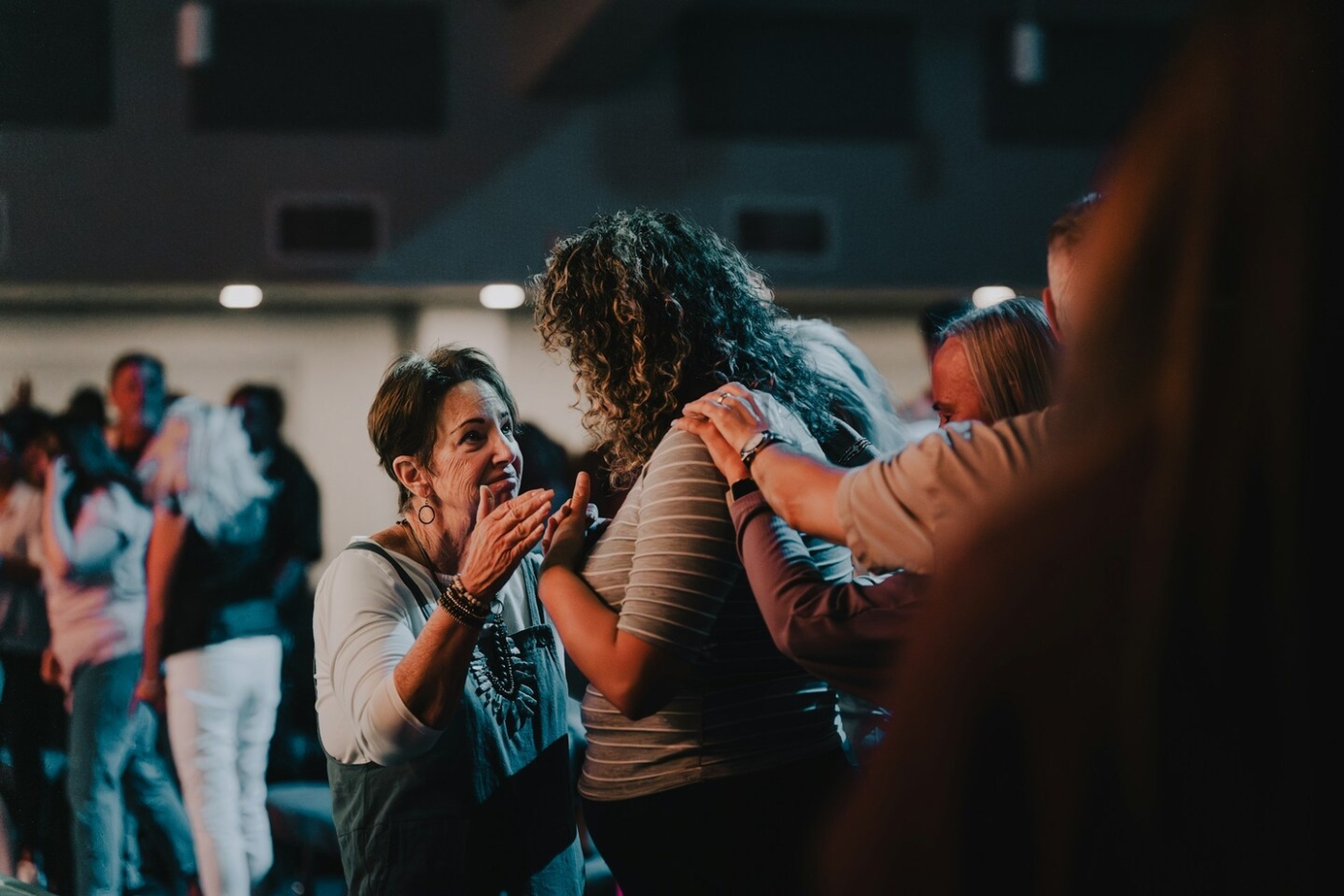 Two women speaking to each other inside a church, with other people standing nearby.