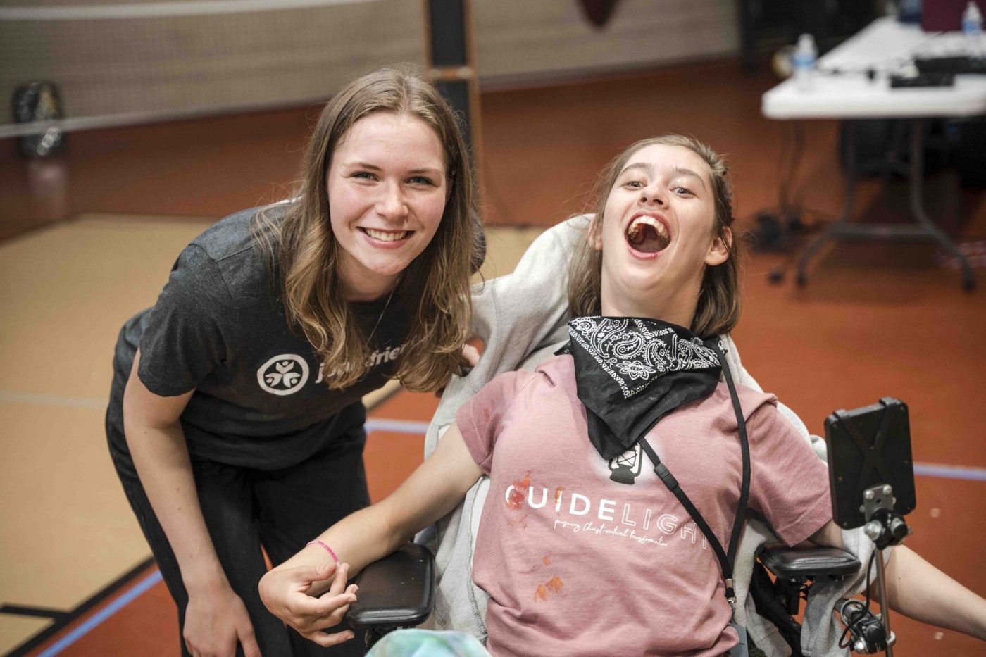 Sophia smiles in her wheelchair with another woman smiling beside her.