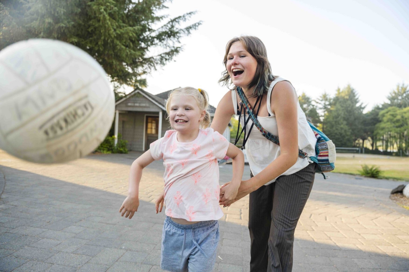 McKenzie plays volleyball with her buddy in front of her.