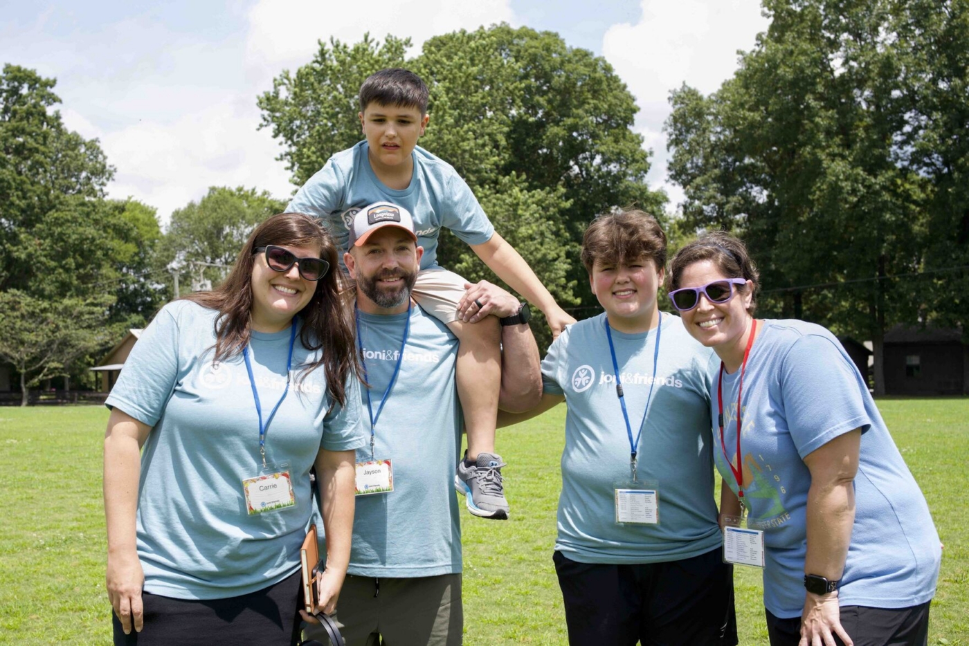 Jayson carrying Collier on his shoulders, posing with Carrie, another boy, and another woman, all smiling at the camera.