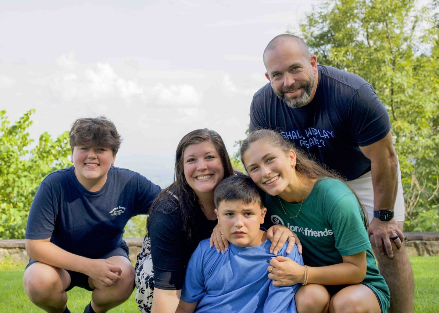 Carrie and Jayson pose with their son Collier, another boy, and a woman, all smiling at the camera.