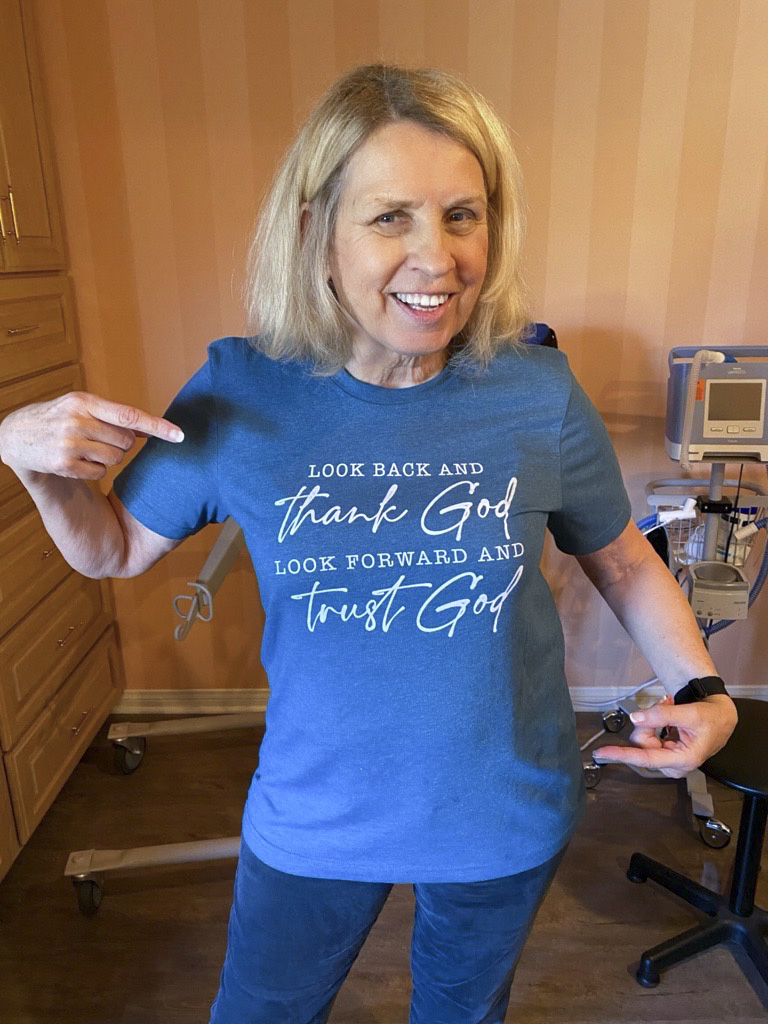 Rainey in a blue shirt that says, "Look back and thank God. Look forward and trust God.