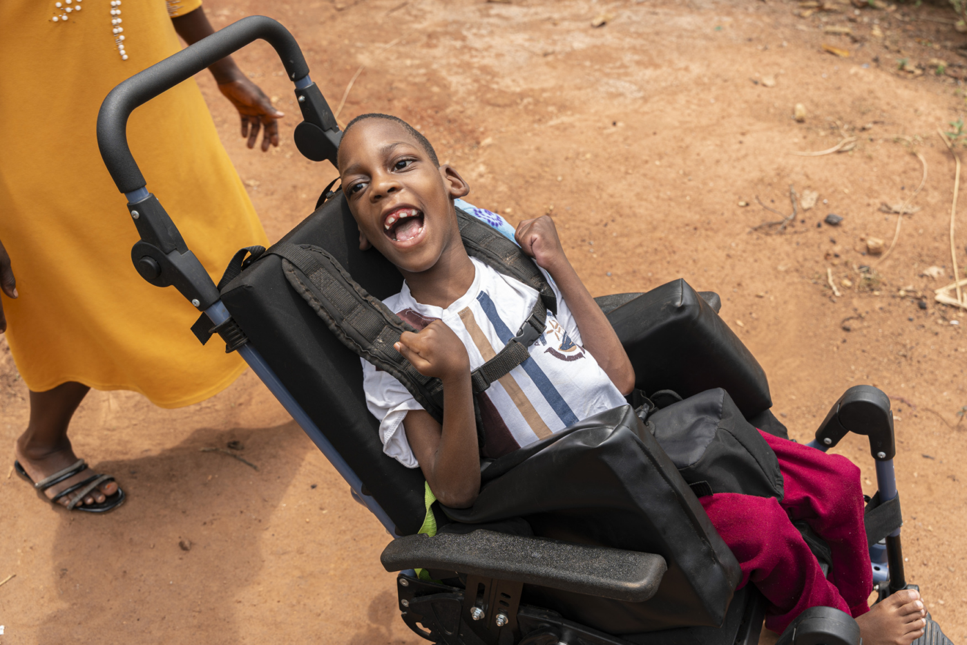 A boy sitting in a new Cub wheelchair, smiling and looking excited.