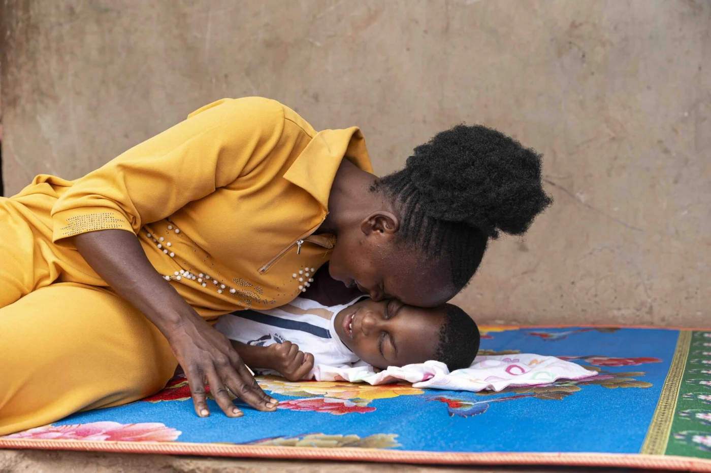 A warm moment of Favour lying on a mat, touching foreheads with his mom.
