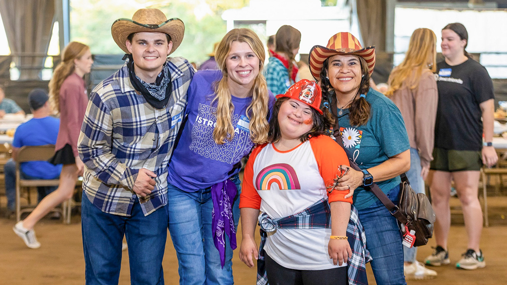People in cowboy and firefighter hats pose for a photo
