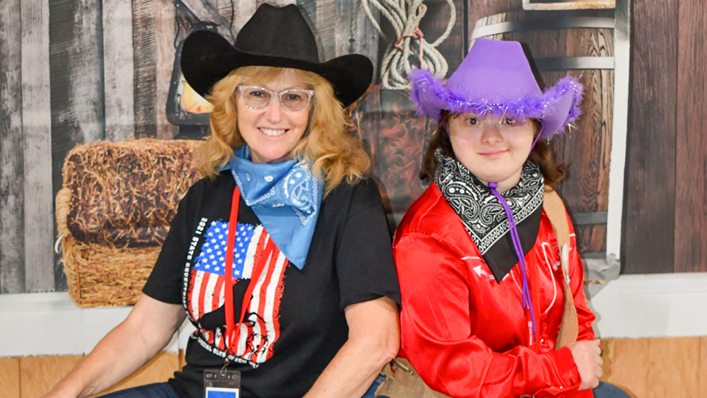 Two people in cowboy hats pose for a photo